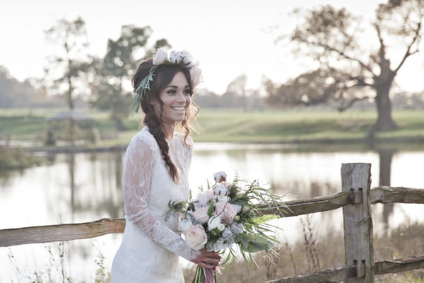 Bride holding bouquet in front of pond