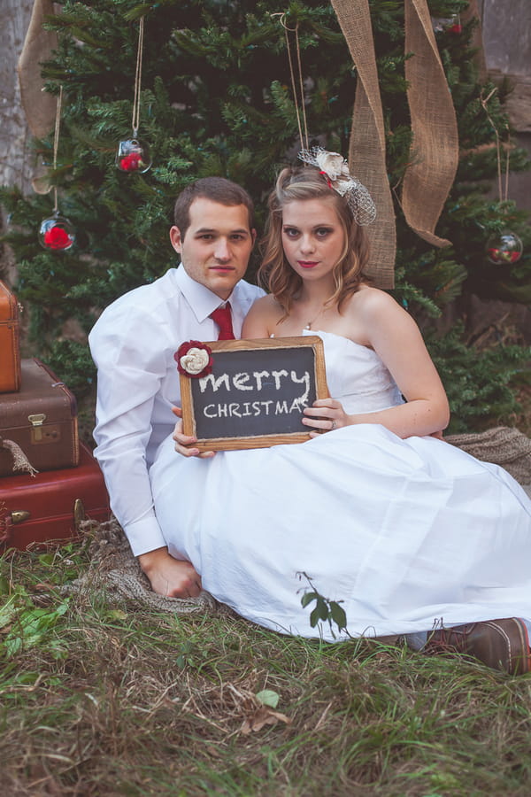 Bride and groom holding merry Christmas sign