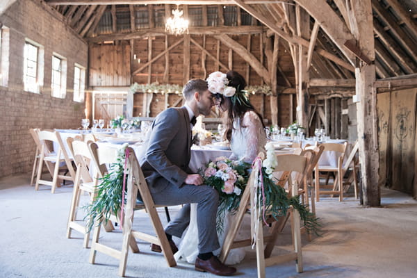 Bride and groom sitting at table in barn