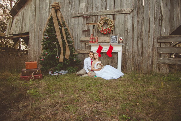 Bride and groom sitting in front of mantelpiece and Christmas tree