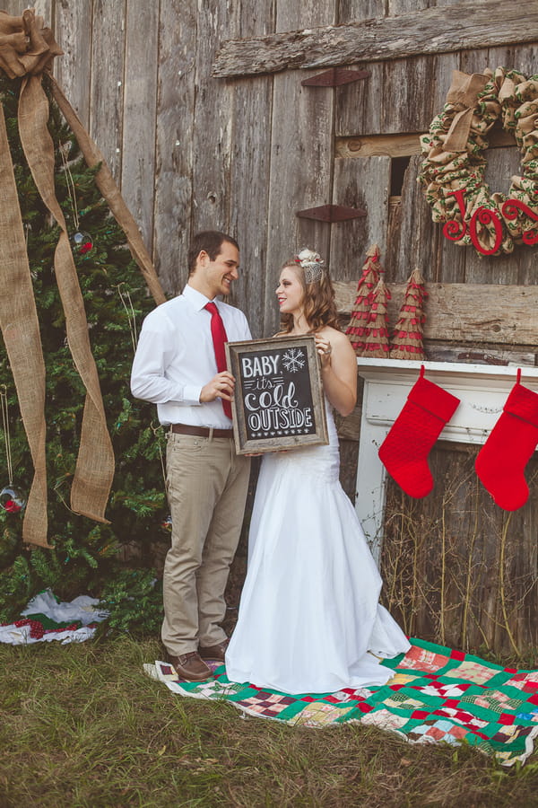 Bride and groom holding 'Baby It's Cold Outside' sign