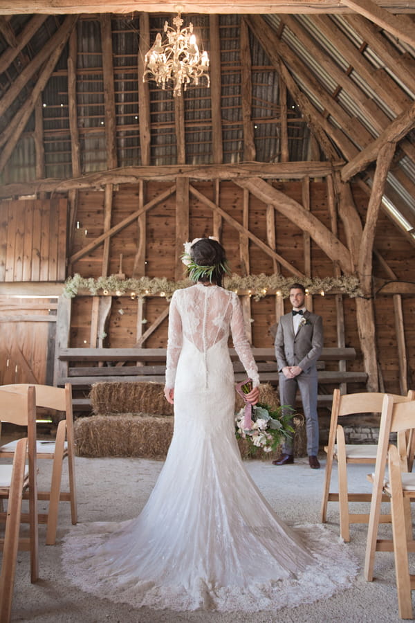 Bride in barn looking at groom