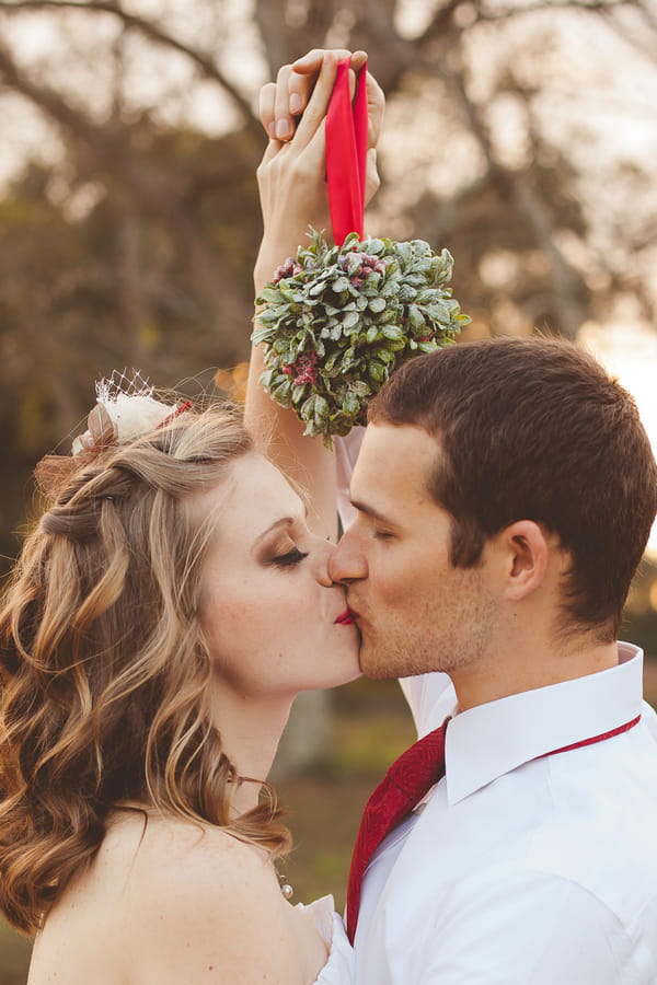 Bride and groom kissing under mistletoe