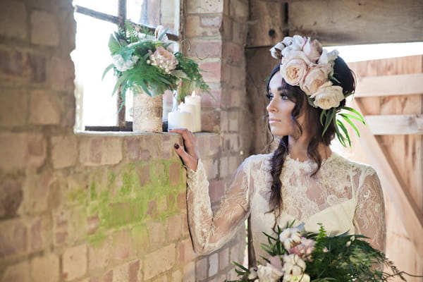 Bride with large floral headpiece looking out of window