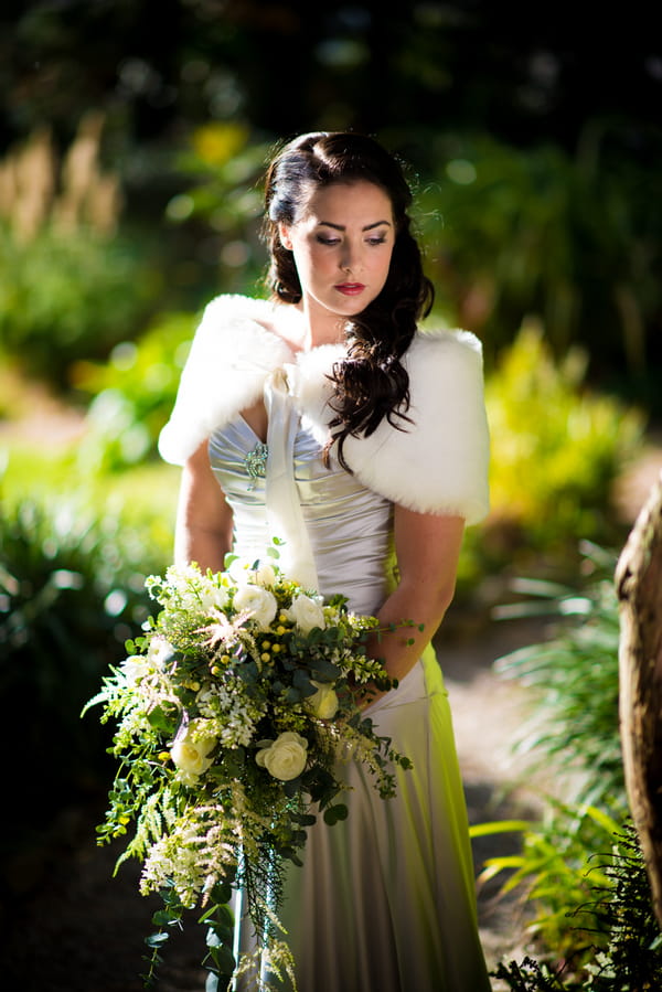 Bride wearing fur shrug holding bouquet