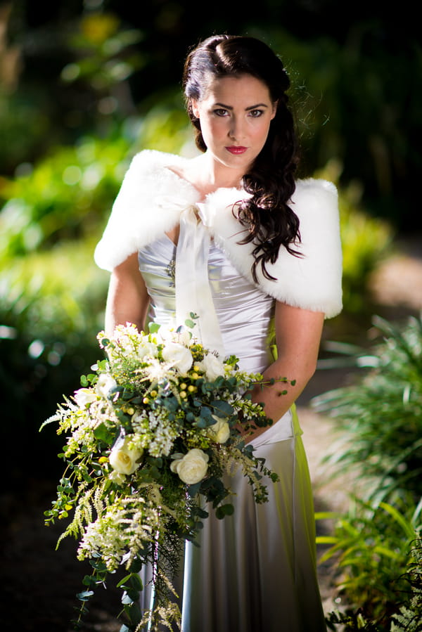 Bride wearing fur shrug holding bouquet