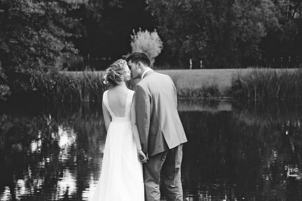 Bride and groom kissing by lake