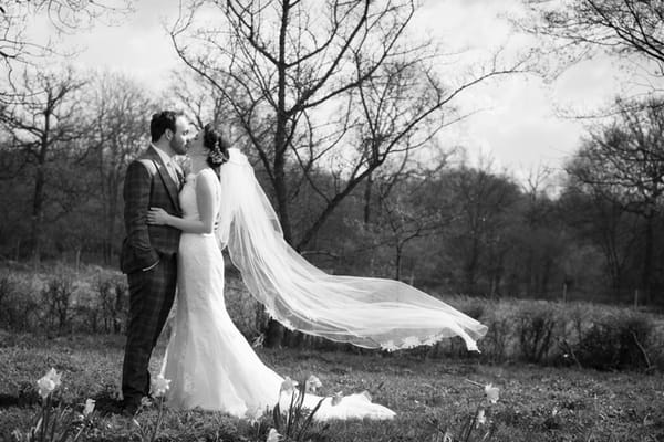 Bride and groom kissing with bride's veil blowing in wind