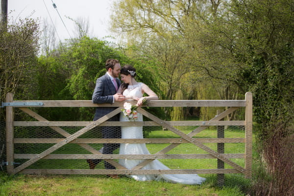 Bride and groom leaning against gate
