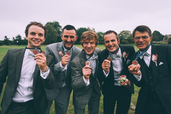 Groom and groomsmen holding out medals