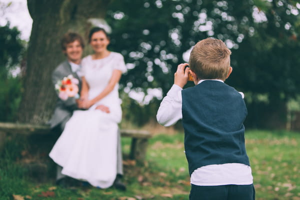 Pageboy taking picture of bride and groom
