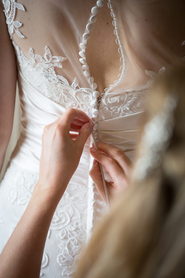 Doing up back of bride's dress