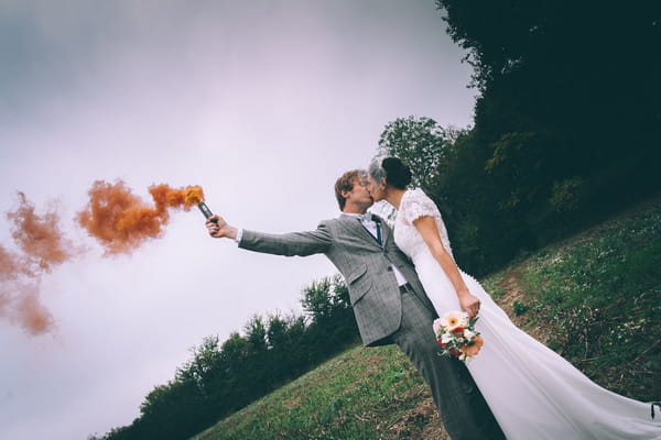 Groom holding flare and kissing bride