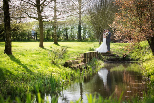 Bride and groom standing by pond