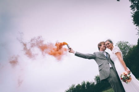 Groom standing with bride holding up a flare