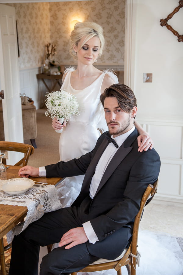 Groom sitting at table with bride standing