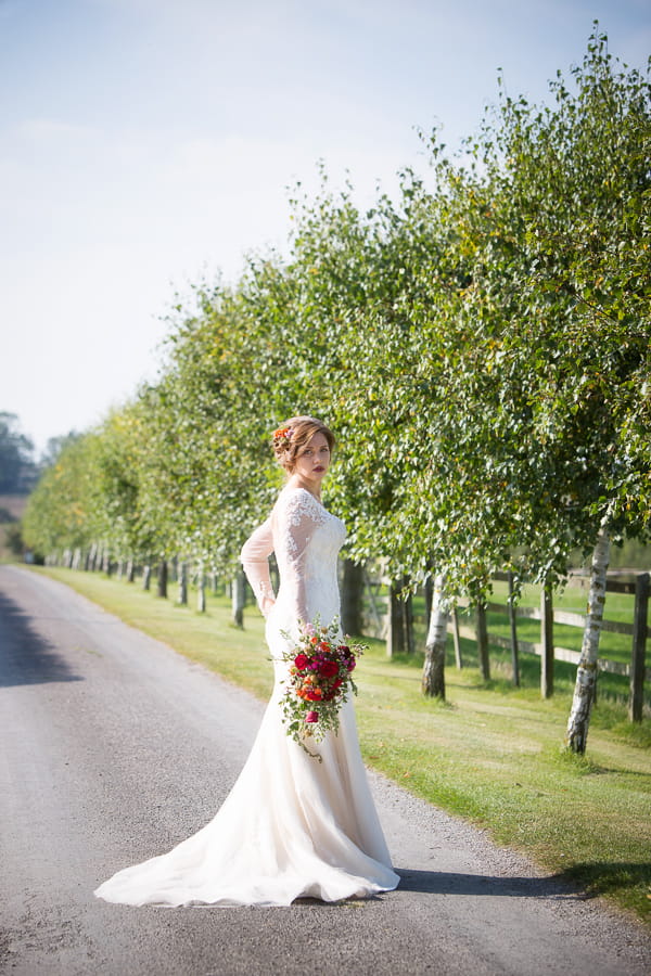 Bride standing in road holding bouquet