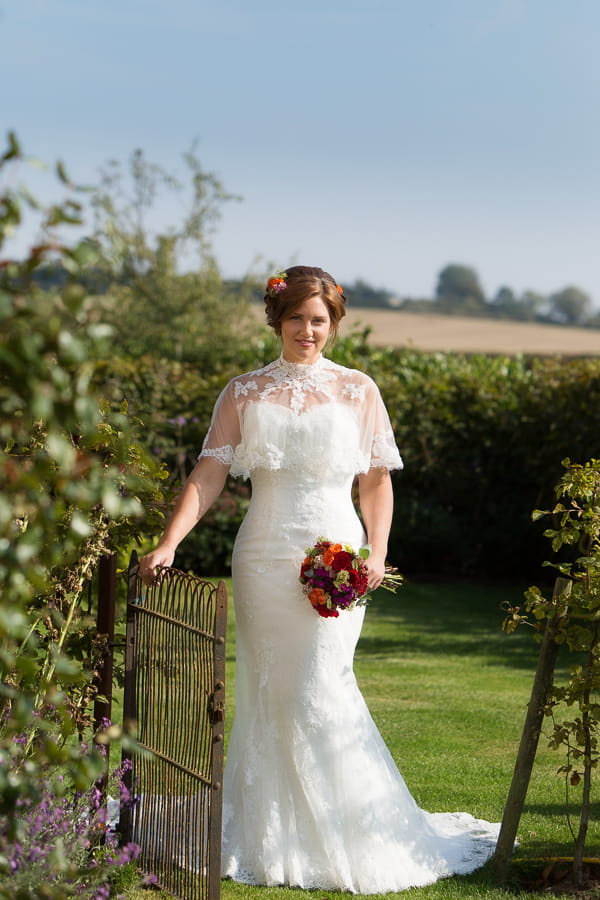 Bride standing by gate holding bouquet