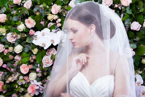 Bride with veil in front of flower wall