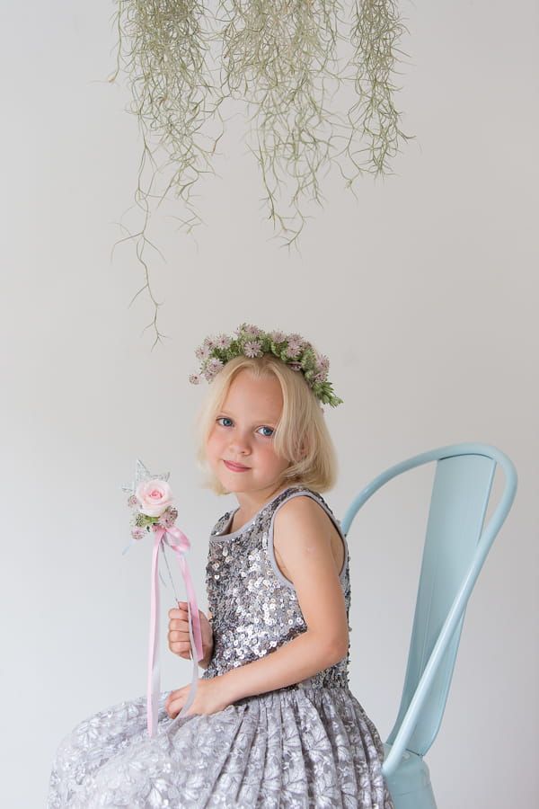 Flower girl sitting on a chair holding a rose star wand