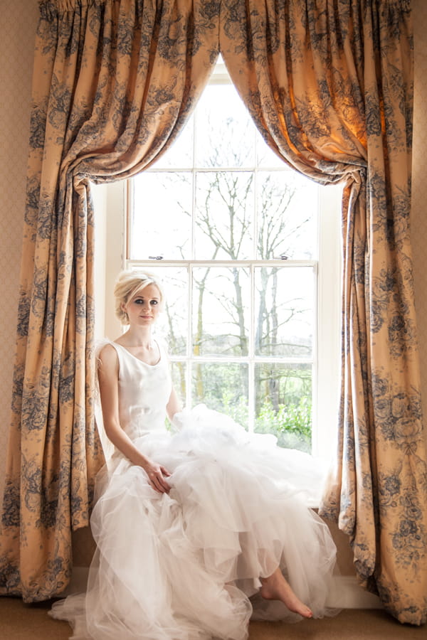 Bride sitting on window ledge