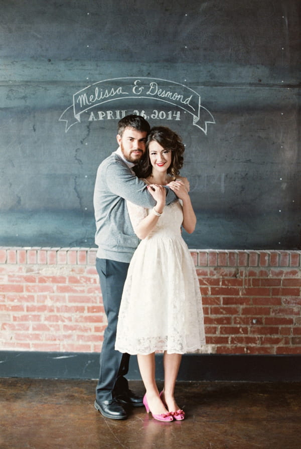 Couple in front of wedding sign written on chalkboard