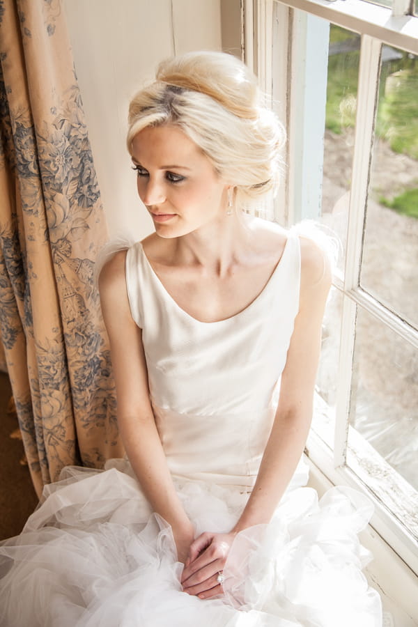 Bride sitting on window ledge