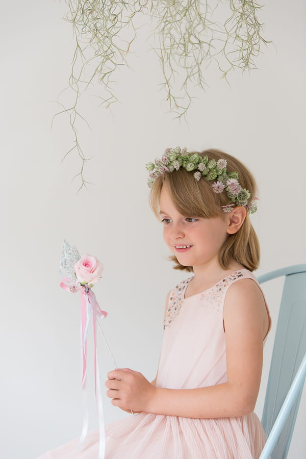 Flower girl sitting holding a rose star wand