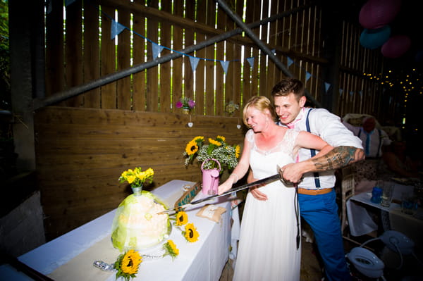 Bride and groom cutting cake with sword