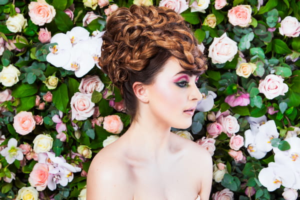 Bride with updo in front of flower wall
