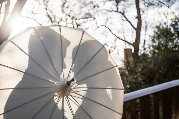 Silhouettes of bride and groom behind parasol