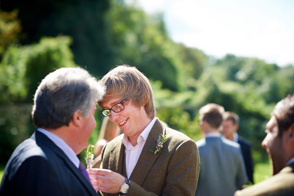 Groom helping man with buttonhole