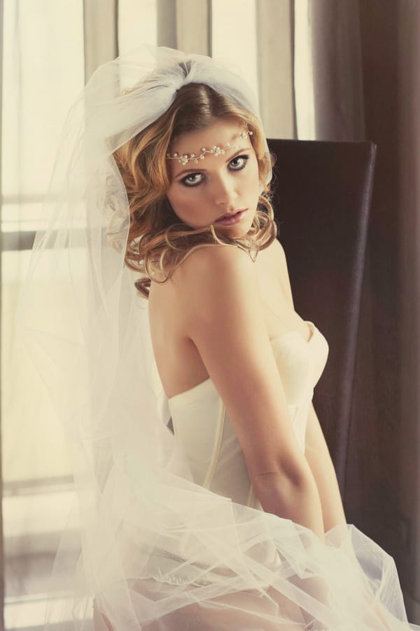 Woman with corset and bridal veil sitting on bed - Bridal boudoir shoot