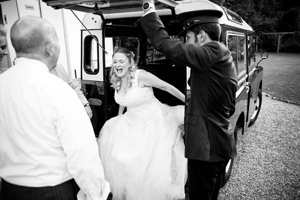 Bride laughing as she gets out of Land Rover wedding car