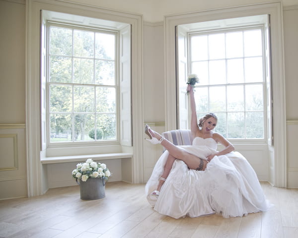 Bride holding bouquet in air and kicking leg out