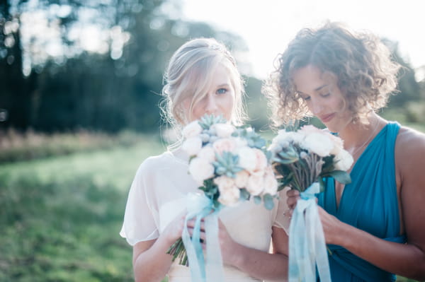 Bride and bridesmaid smelling bouquets