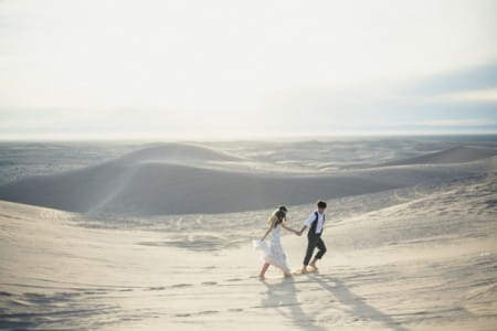 Bride and groom walking across desert
