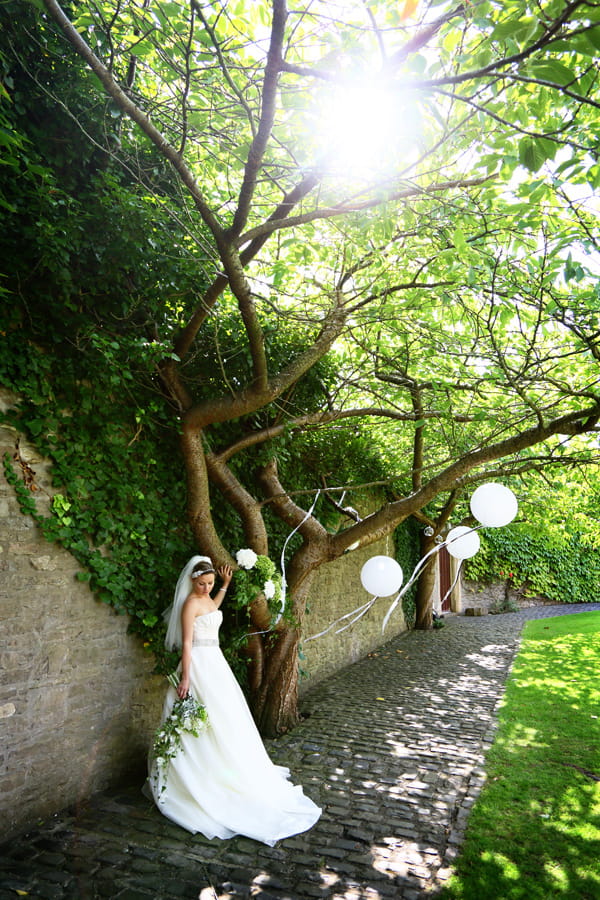 Bride next to wishing tree in Walton Castle garden