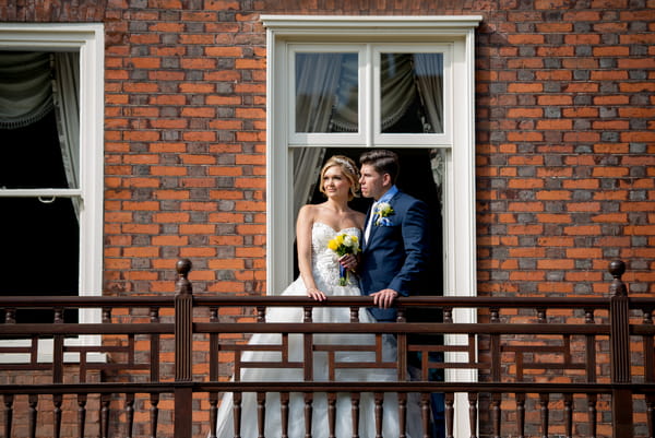 Bride and groom standing on balcony