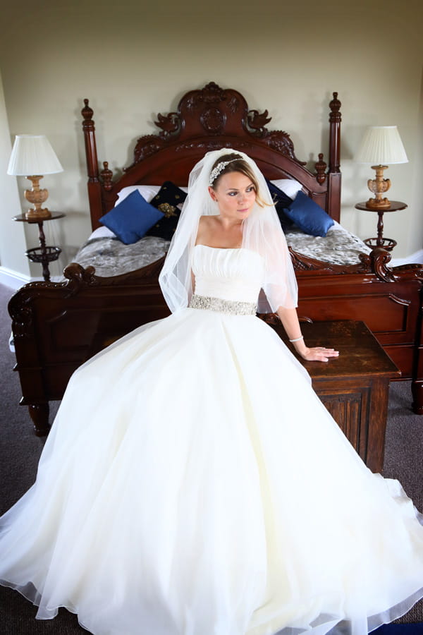 Bride sitting on chest at end of bed