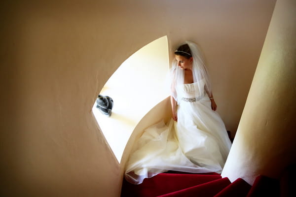 Bride standing on spiral staircase looking out of window