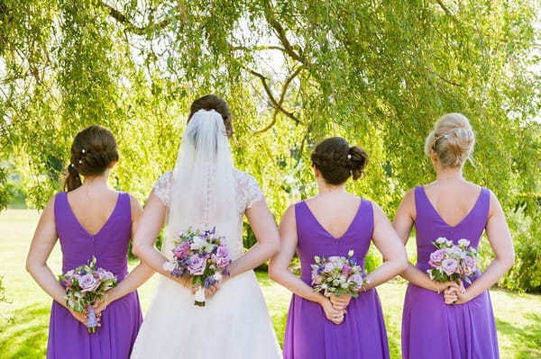Bride and bridesmaids holding bouquets behind their backs
