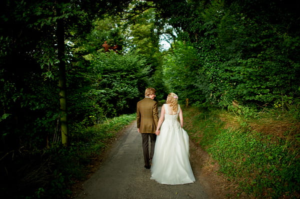 Bride and groom walking down country lane