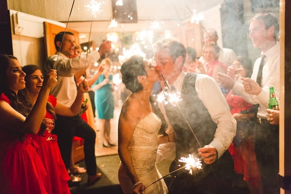 Bride and groom kiss holding sparklers