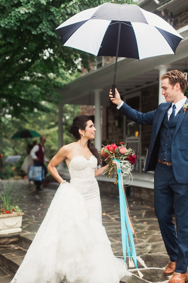 Groom holding umbrella over bride