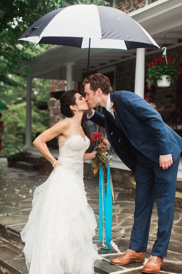 Bride and groom kiss under umbrella