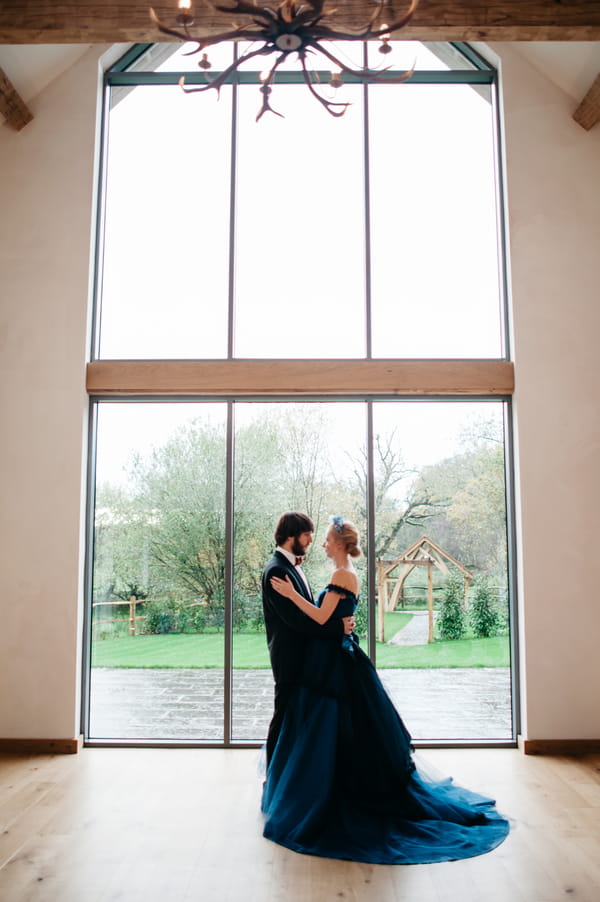 Bride and groom standing by large window