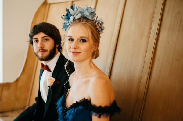 Bride with blue wedding dress and blue hairpiece sitting next to groom