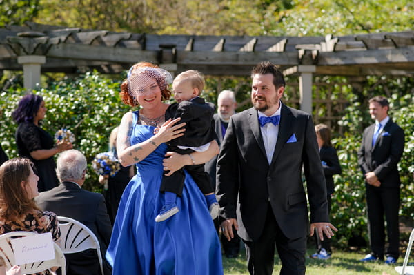 Bride in blue dress carrying young boy