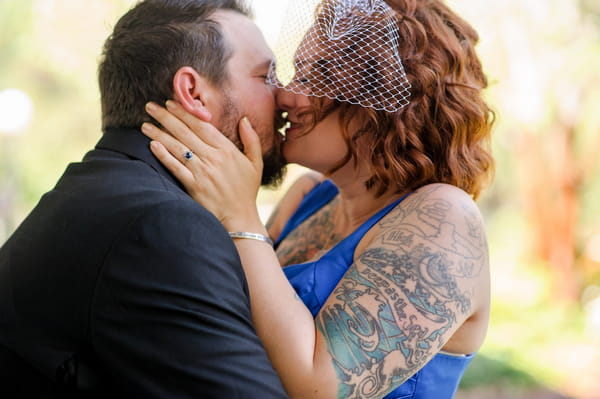 Groom kissing bride with tattoos